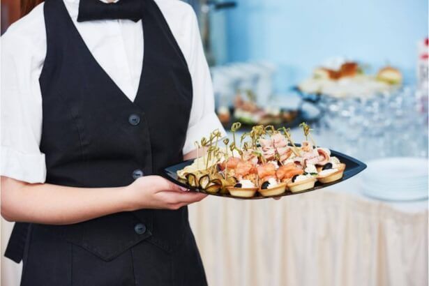 Camarera con bandeja de canapés durante un cóctel